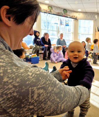 Woman with baby in room with families during a storytime